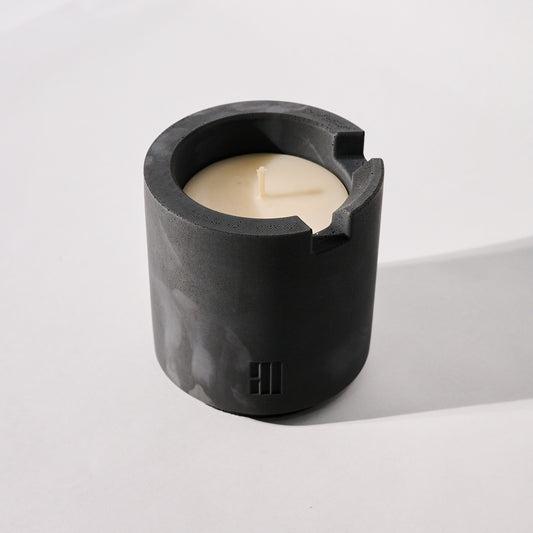 Concrete Crenel candle vessel with a white candle inside on a white background