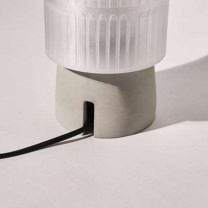 White textured lamp with a black cord on a light gray background