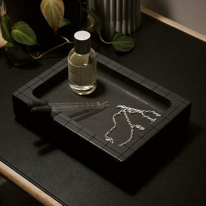 black concrete valet tray by illfound with necklace and perfume on a black desk