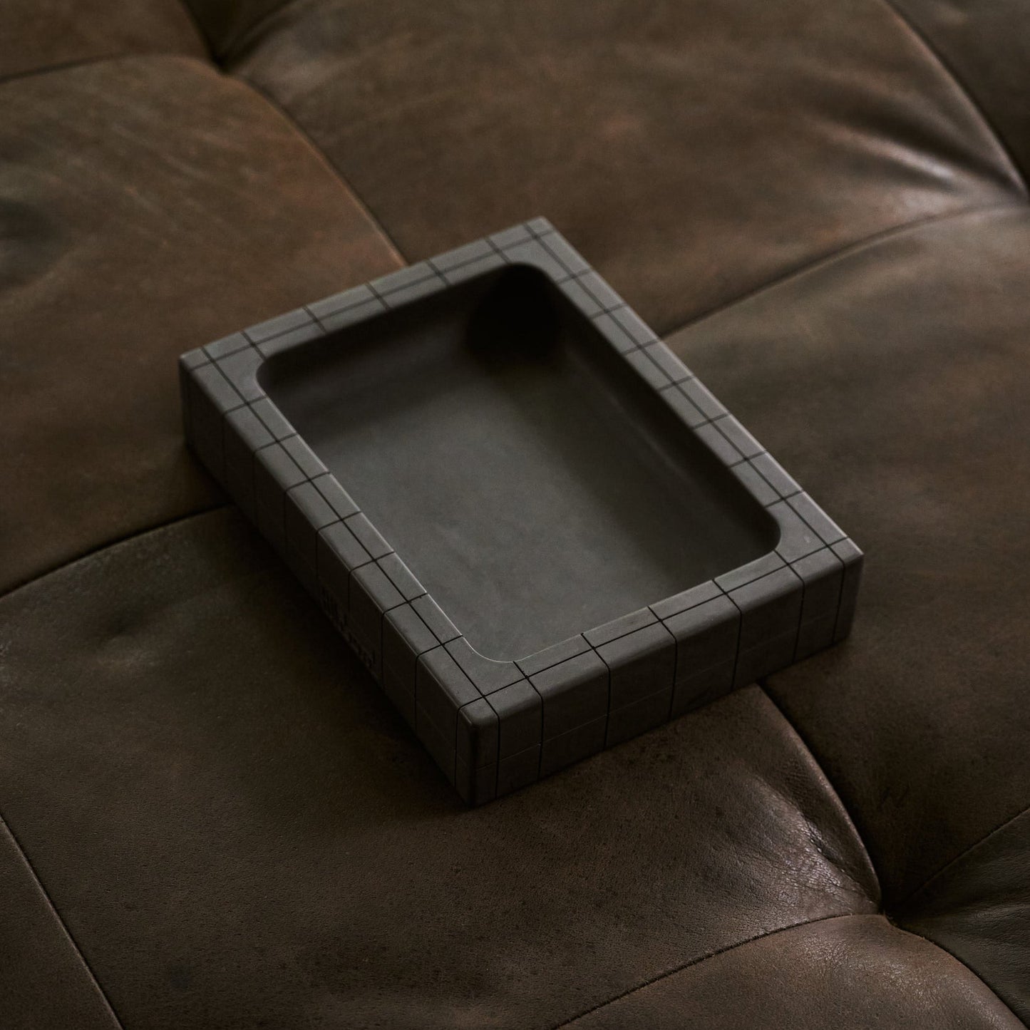 Valet tray in black sitting on leather ottoman by illfound