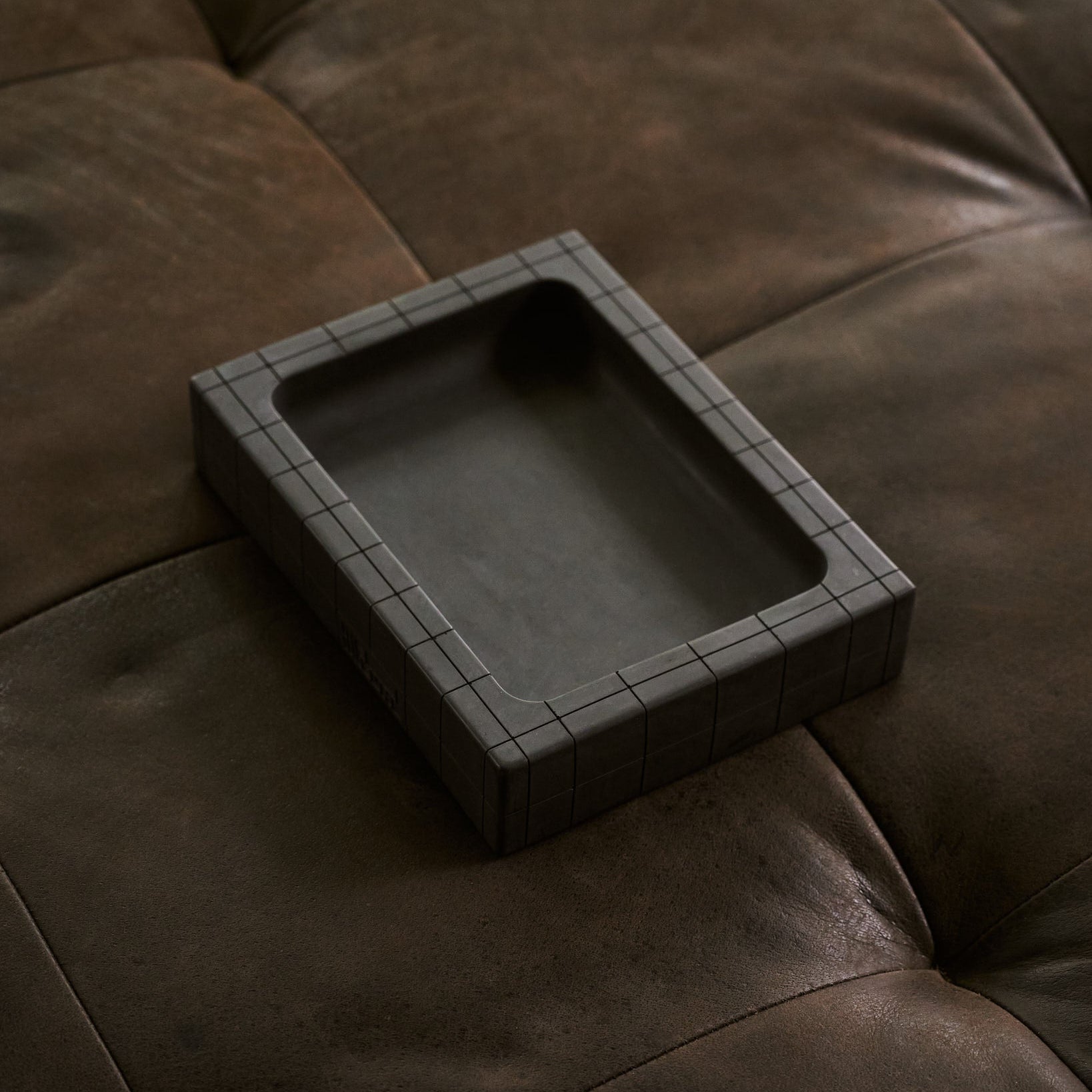 Valet tray in black sitting on leather ottoman by illfound